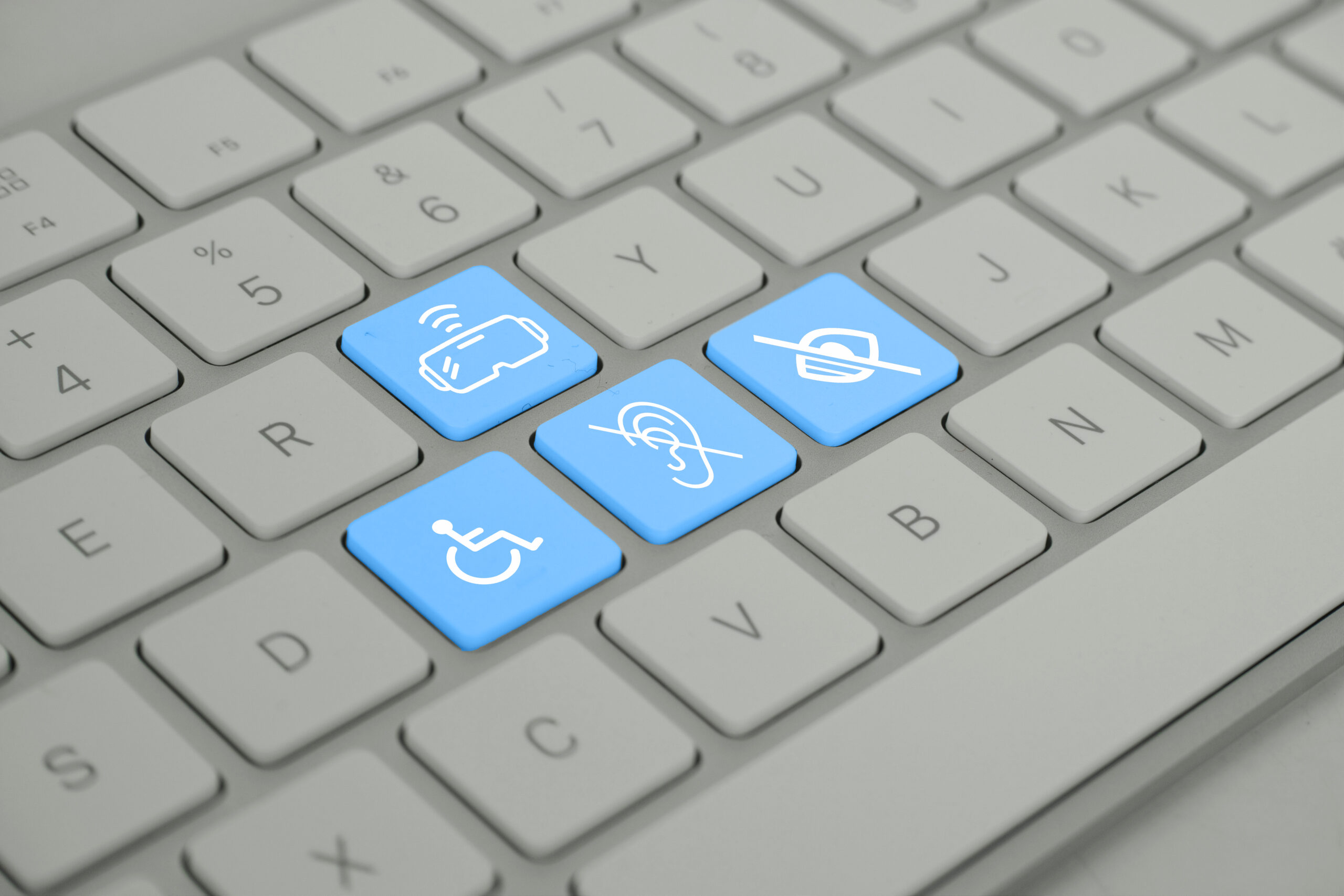Closeup of computer keyboard with keys highlighting a wheelchair icon, a deaf/hard of hearing icon, and a blind/low vision icon.